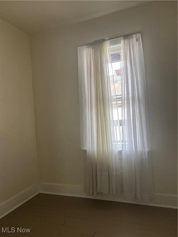 unfurnished room featuring dark wood-type flooring and baseboards