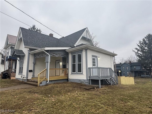 view of front of property with a porch, roof with shingles, a chimney, and a front lawn