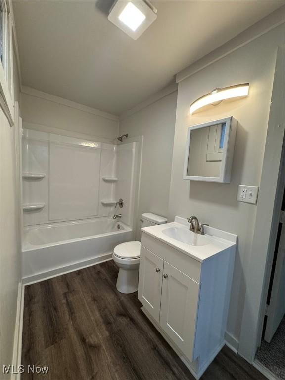 bathroom featuring shower / bath combination, toilet, ornamental molding, vanity, and wood finished floors