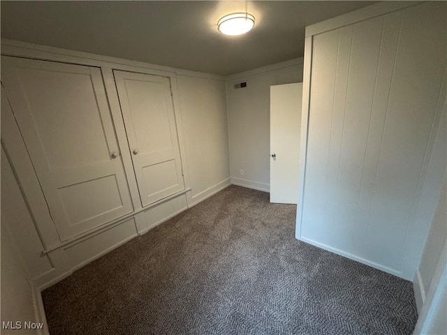 unfurnished bedroom with visible vents and dark carpet