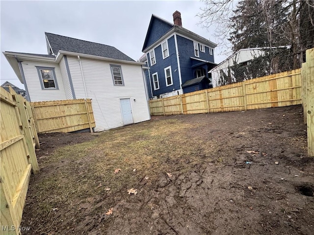 rear view of house with a chimney and a fenced backyard