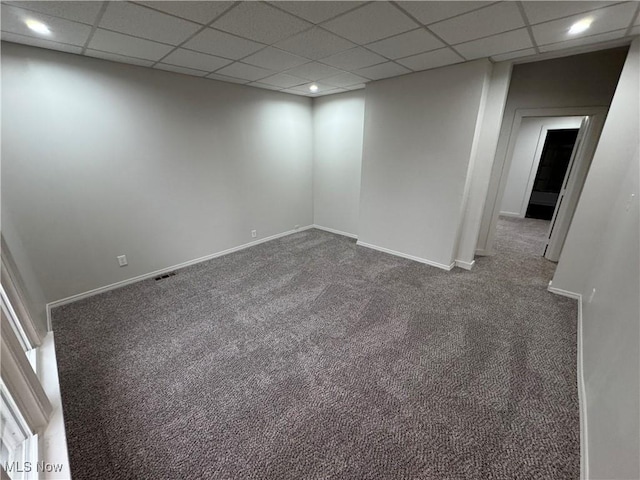 unfurnished room featuring carpet floors, visible vents, baseboards, and a drop ceiling