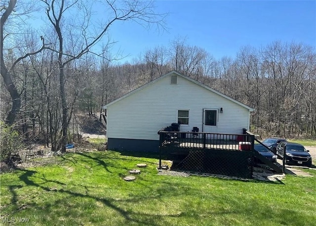 view of home's exterior featuring a lawn, a wooden deck, and a view of trees