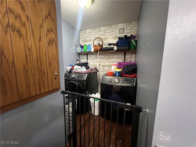 interior space with a textured ceiling, laundry area, washing machine and dryer, and an accent wall