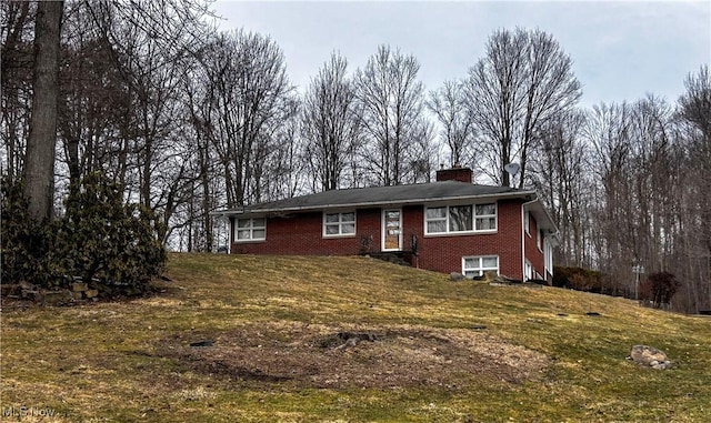 ranch-style house featuring a front yard, brick siding, and a chimney