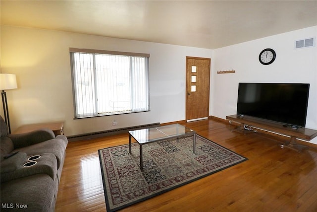 living room featuring baseboards, visible vents, baseboard heating, and wood finished floors