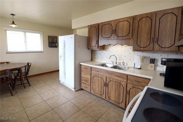 kitchen featuring electric range, a sink, light countertops, white fridge with ice dispenser, and backsplash