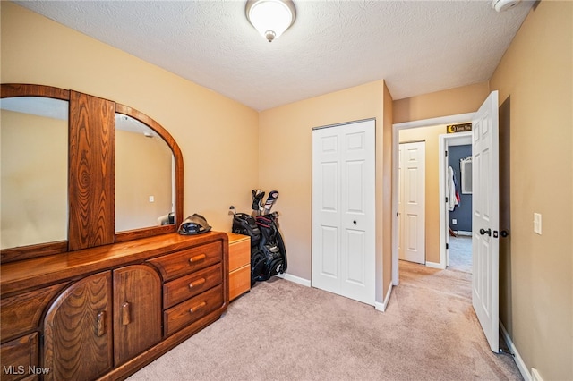 bedroom featuring light carpet, a textured ceiling, and baseboards