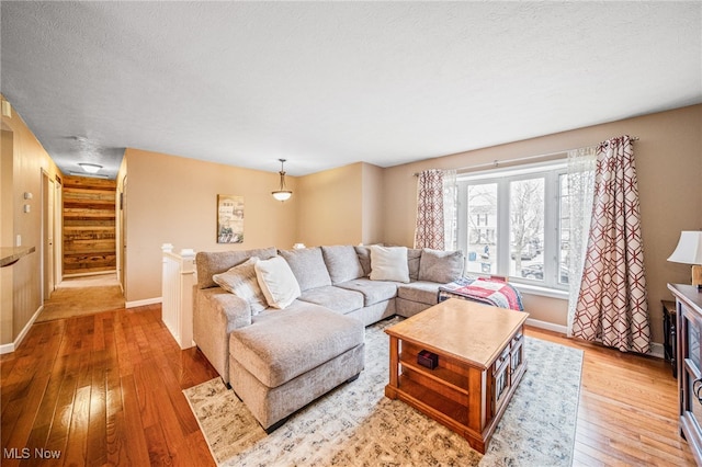 living area with light wood-type flooring, french doors, a textured ceiling, and baseboards