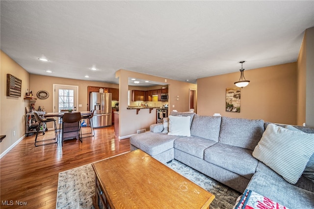 living room with wood-type flooring, baseboards, and recessed lighting