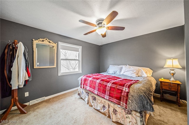 bedroom with a textured ceiling, carpet flooring, a ceiling fan, visible vents, and baseboards