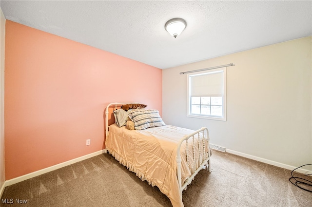 bedroom with visible vents, a textured ceiling, baseboards, and carpet flooring