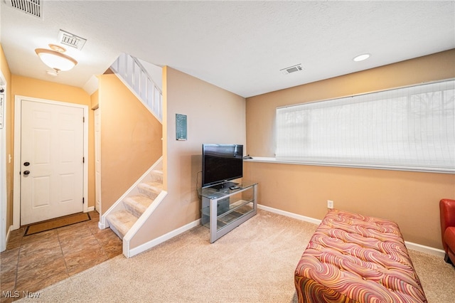 sitting room with carpet floors, visible vents, and stairs