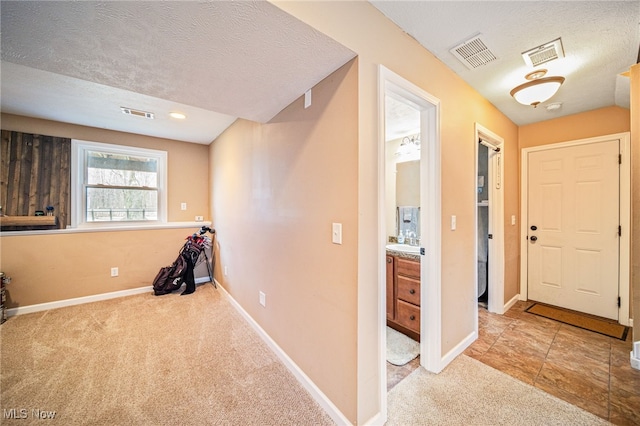 interior space with a textured ceiling, visible vents, and baseboards