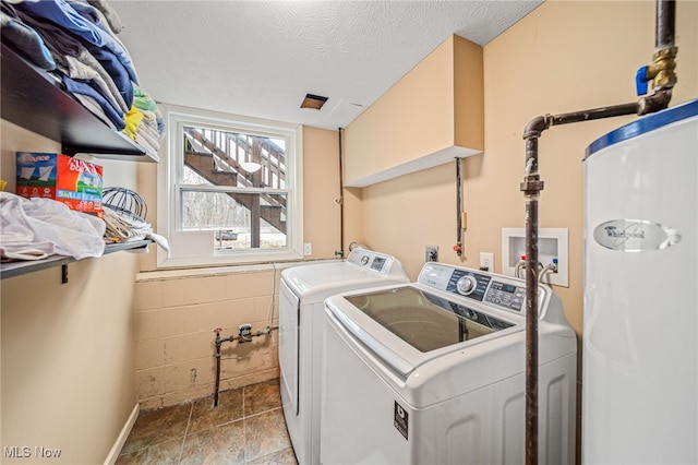 laundry area featuring laundry area, water heater, washer and dryer, and a textured ceiling