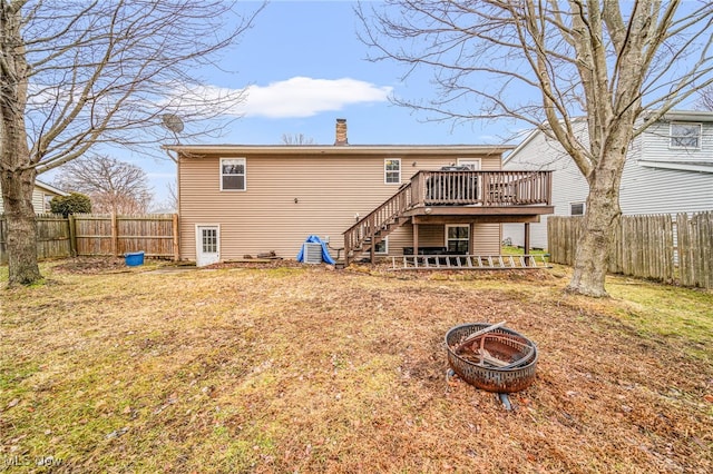 back of property featuring a deck, a fenced backyard, a fire pit, stairs, and a chimney