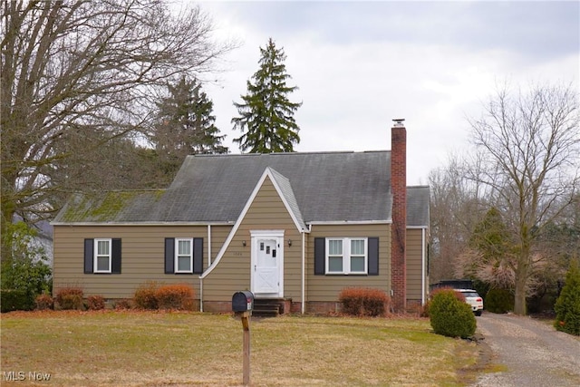 view of front of house featuring a chimney, gravel driveway, a front yard, and roof with shingles