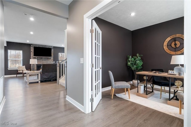 home office with recessed lighting, a large fireplace, baseboards, and wood finished floors