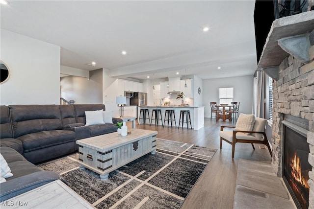 living area with a stone fireplace, dark wood finished floors, and recessed lighting