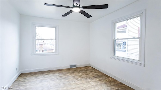 empty room featuring light wood finished floors, baseboards, visible vents, and a ceiling fan