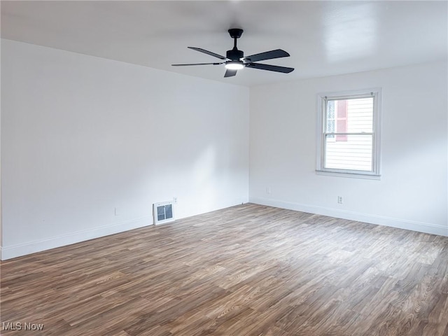 spare room featuring ceiling fan, baseboards, and wood finished floors