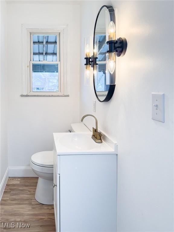 bathroom with baseboards, vanity, toilet, and wood finished floors