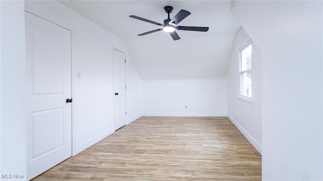 additional living space with vaulted ceiling, light wood finished floors, a ceiling fan, and baseboards