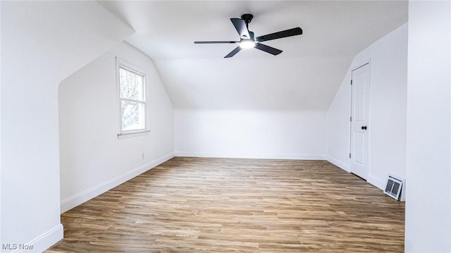 additional living space featuring visible vents, a ceiling fan, vaulted ceiling, wood finished floors, and baseboards