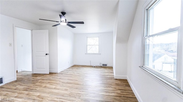 spare room featuring a ceiling fan, visible vents, baseboards, and wood finished floors