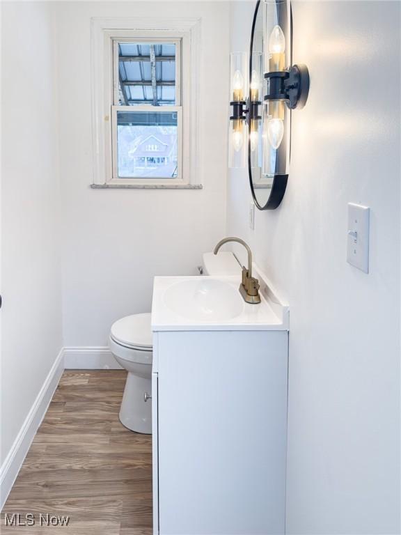 bathroom featuring toilet, wood finished floors, vanity, and baseboards