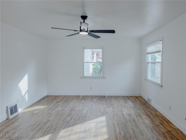 unfurnished room featuring a ceiling fan, visible vents, baseboards, and wood finished floors