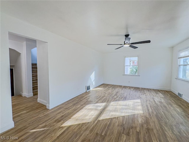 spare room with stairs, visible vents, baseboards, and wood finished floors