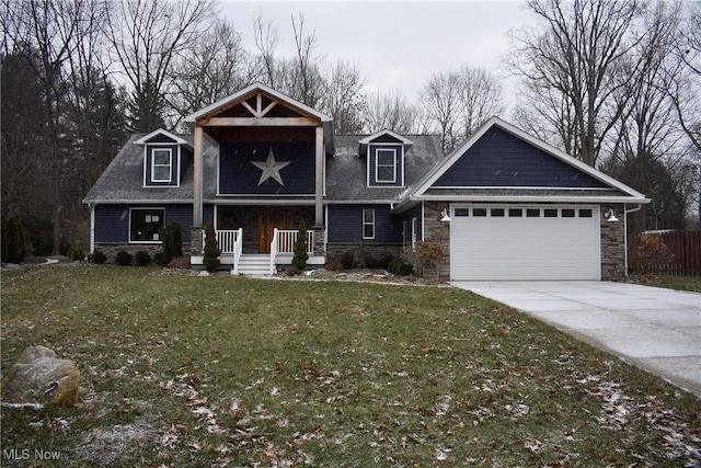 view of front of home with a porch, an attached garage, stone siding, driveway, and a front lawn