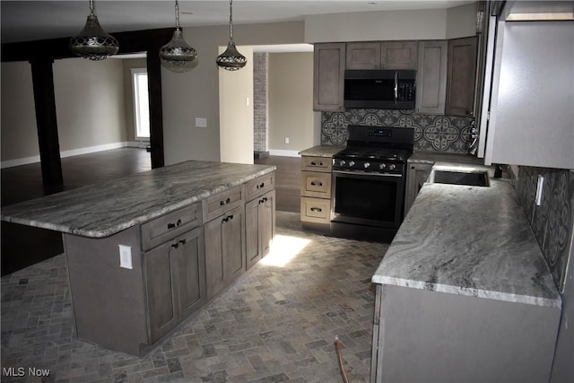 kitchen with decorative backsplash, black gas range oven, stainless steel microwave, a center island, and a sink