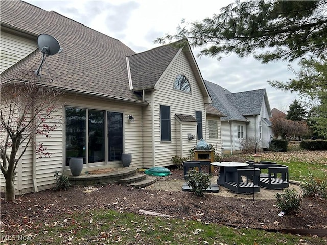 rear view of house featuring a patio and roof with shingles