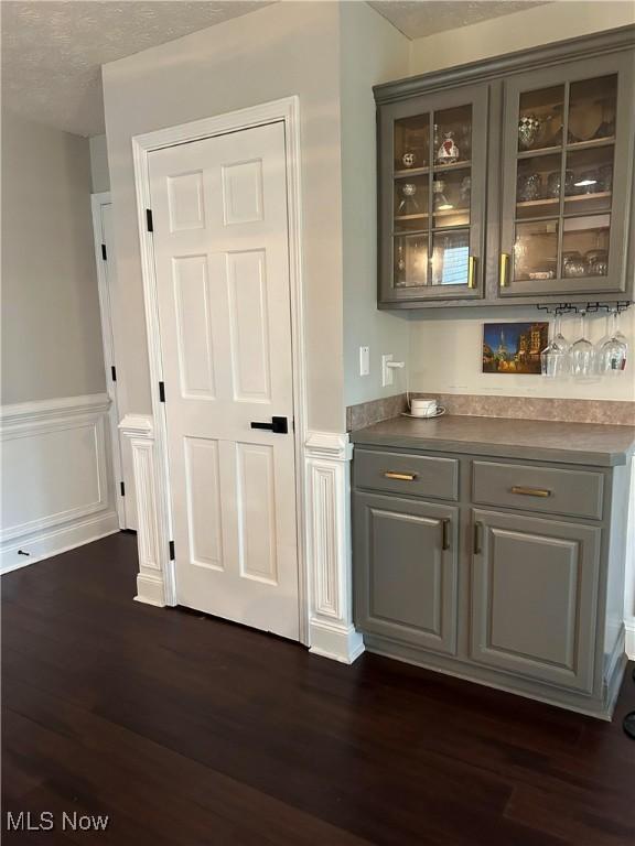 bar featuring dark wood-style floors, a dry bar, and wainscoting