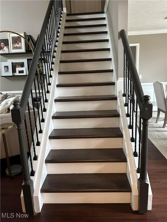 staircase featuring ornamental molding and wood finished floors