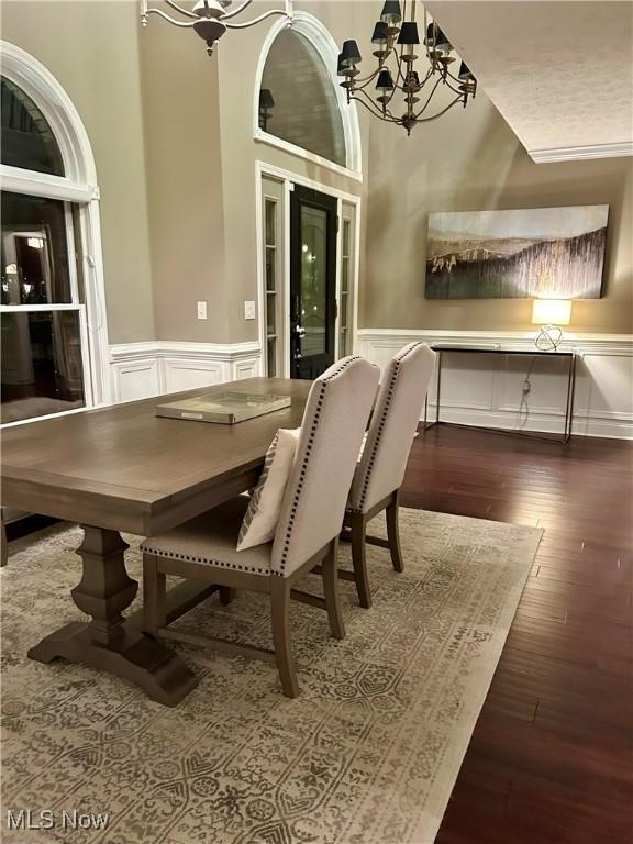 dining area with a wainscoted wall, a chandelier, a decorative wall, and wood finished floors