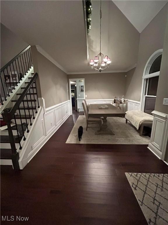 game room featuring dark wood-style floors, a wainscoted wall, a decorative wall, an inviting chandelier, and ornamental molding