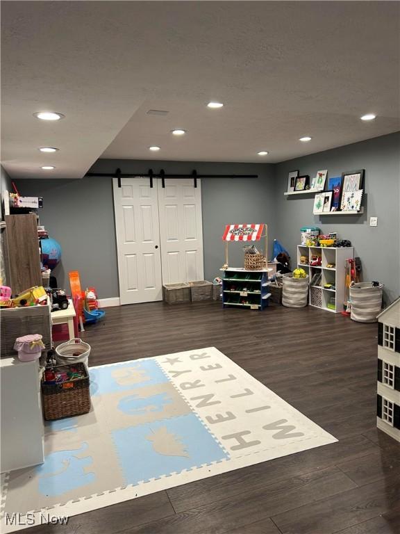 rec room featuring recessed lighting, wood finished floors, a textured ceiling, and a barn door