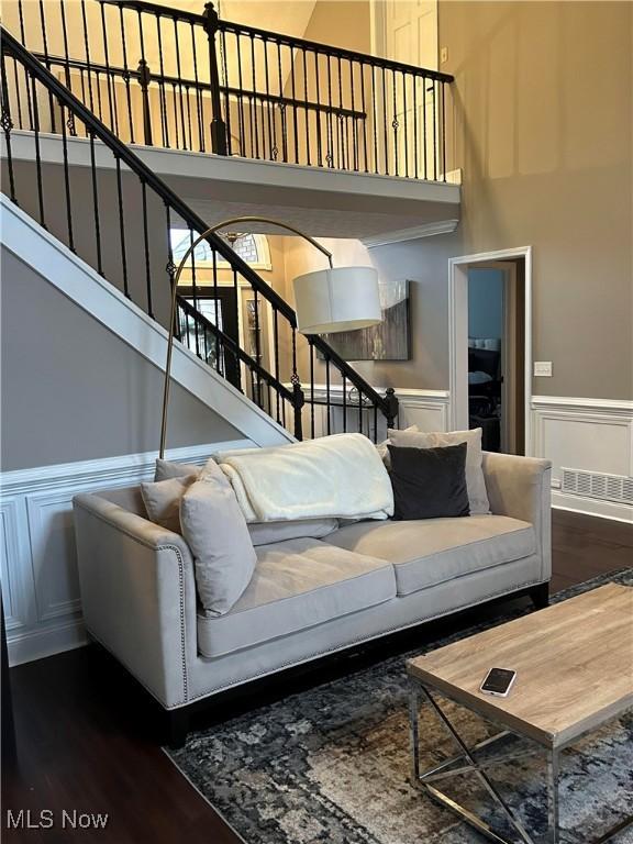 living area featuring a wainscoted wall, stairs, a high ceiling, and wood finished floors