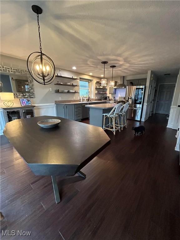 unfurnished dining area with a textured ceiling, a sink, dark wood finished floors, and a notable chandelier