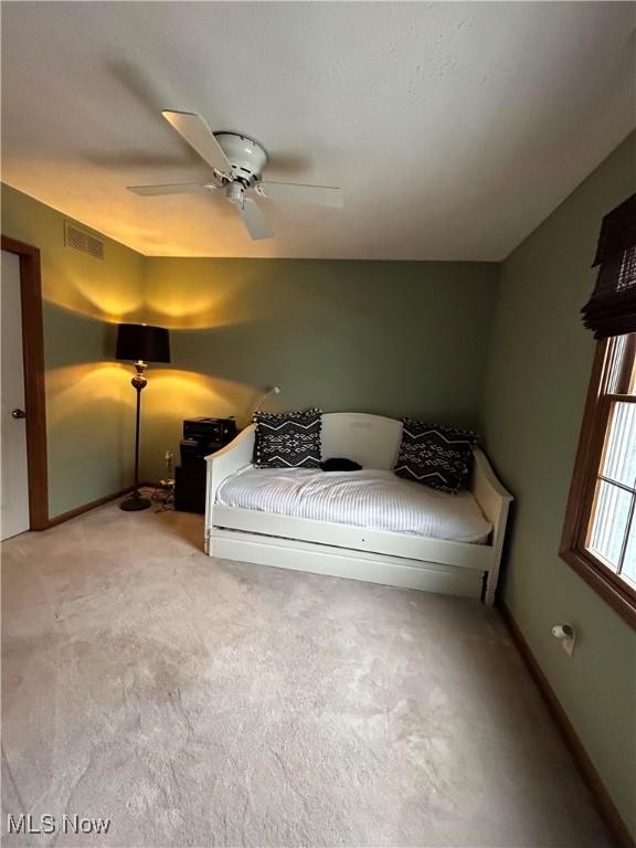 carpeted bedroom featuring ceiling fan, visible vents, and baseboards