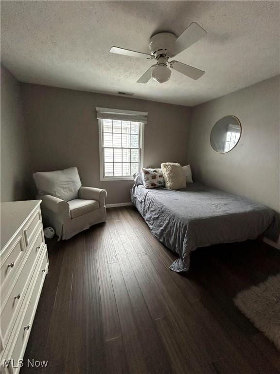 bedroom with ceiling fan, a textured ceiling, baseboards, and dark wood-style flooring