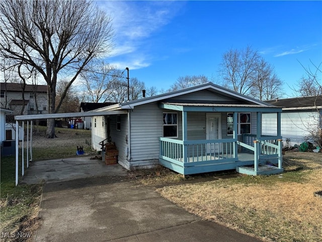 view of front of house featuring covered porch, a carport, a front yard, and driveway