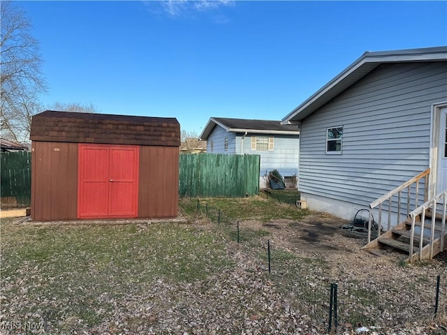 view of yard featuring fence, a storage unit, and an outdoor structure