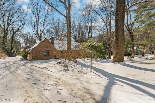 snowy yard featuring a storage shed and an outdoor structure