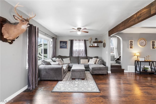 living room featuring arched walkways, beam ceiling, a ceiling fan, wood finished floors, and baseboards