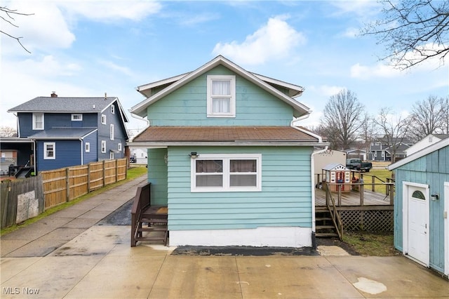 rear view of property featuring a deck, a patio, fence, and a residential view