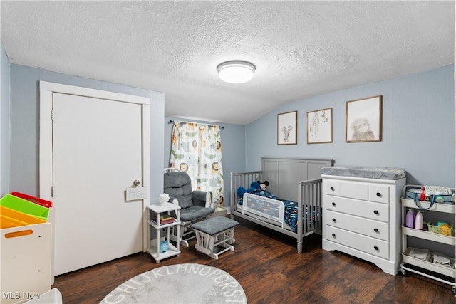 bedroom with vaulted ceiling, a textured ceiling, and wood finished floors